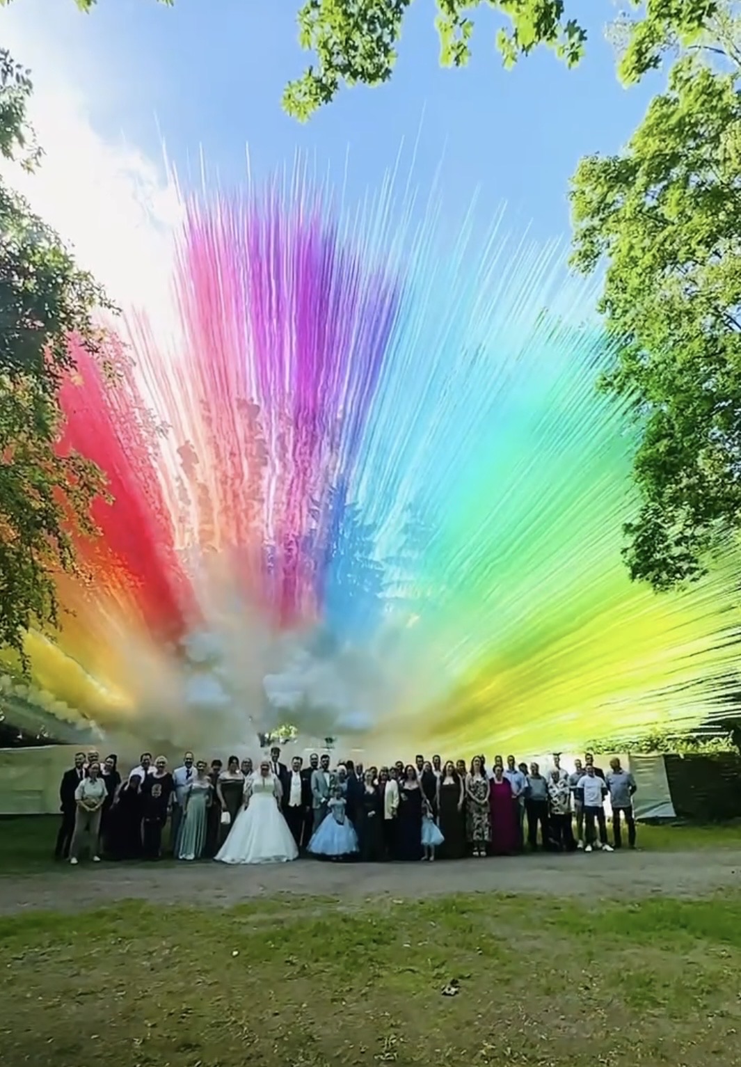 Brautpaar und Hochzeitsgäste vor einer spektakulären Farbpulver-Explosion im Garten des Hotel Seeschloss am Bötzsee. Bunte Farben steigen in den Himmel und schaffen einen außergewöhnlichen Höhepunkt der Hochzeitsfeier.